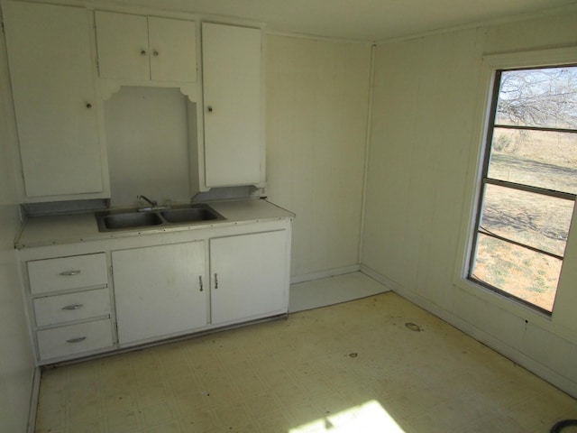 kitchen featuring white cabinetry, light countertops, light floors, and a sink