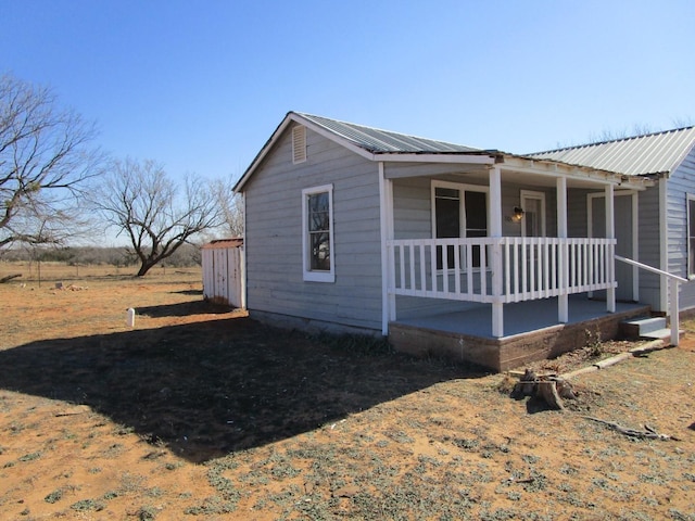 view of side of property featuring metal roof and covered porch