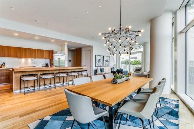 dining space with light wood-style flooring, a notable chandelier, and recessed lighting