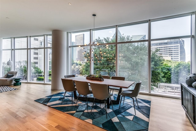 dining space with a wall of windows, an inviting chandelier, and wood finished floors