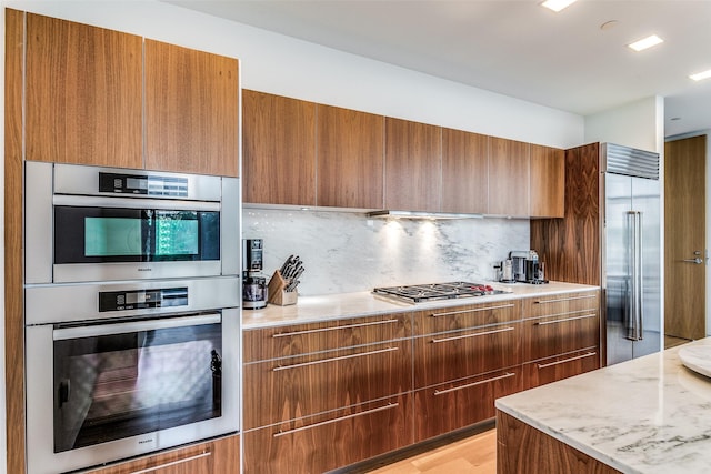 kitchen featuring modern cabinets, brown cabinets, and appliances with stainless steel finishes