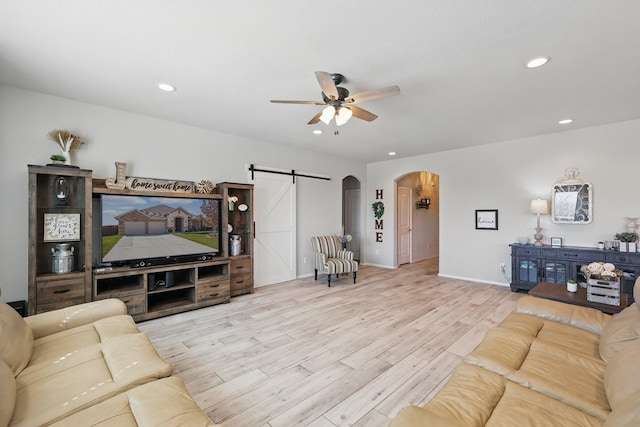 living room featuring a ceiling fan, wood finished floors, recessed lighting, arched walkways, and a barn door