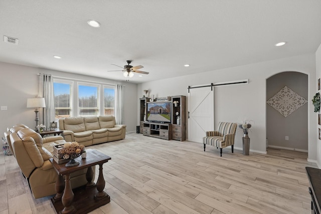 living area featuring visible vents, light wood-style flooring, a ceiling fan, recessed lighting, and a barn door