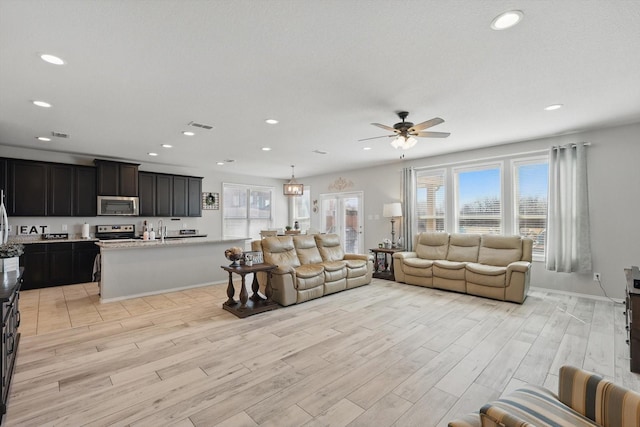 living room with a wealth of natural light, recessed lighting, light wood-style flooring, and ceiling fan