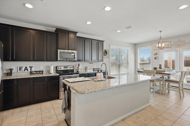 kitchen with visible vents, a sink, stainless steel appliances, light tile patterned floors, and light stone countertops