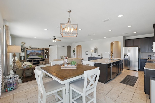 dining room featuring a barn door, light tile patterned floors, recessed lighting, and arched walkways