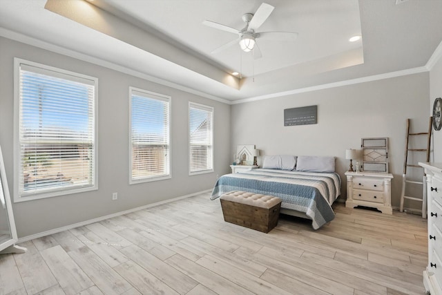 bedroom with a ceiling fan, baseboards, light wood finished floors, a tray ceiling, and crown molding