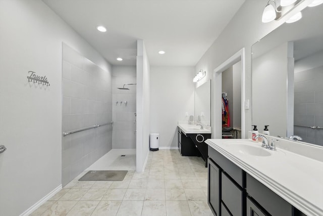 full bathroom with a tile shower, recessed lighting, baseboards, and a sink