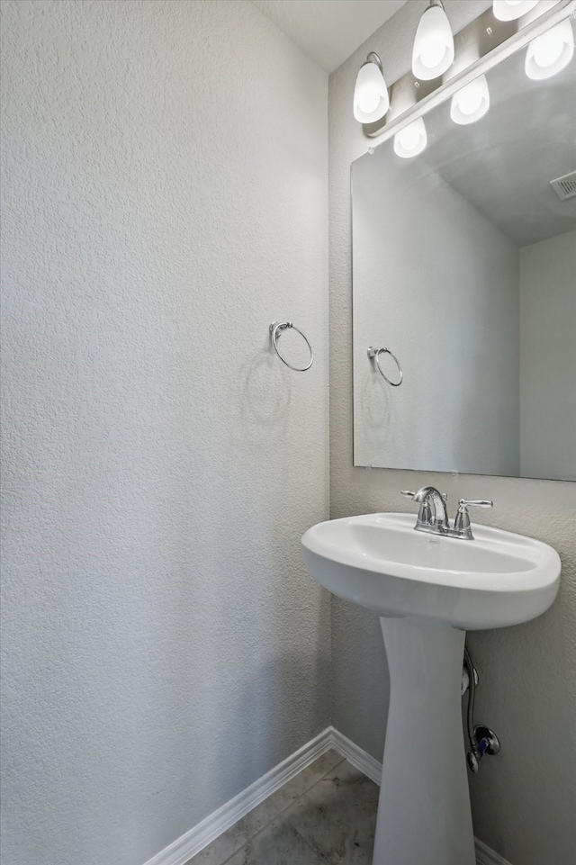 bathroom with a textured wall, visible vents, baseboards, and tile patterned flooring