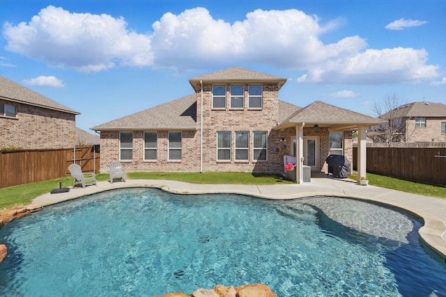 rear view of property with brick siding, a patio area, and a fenced backyard