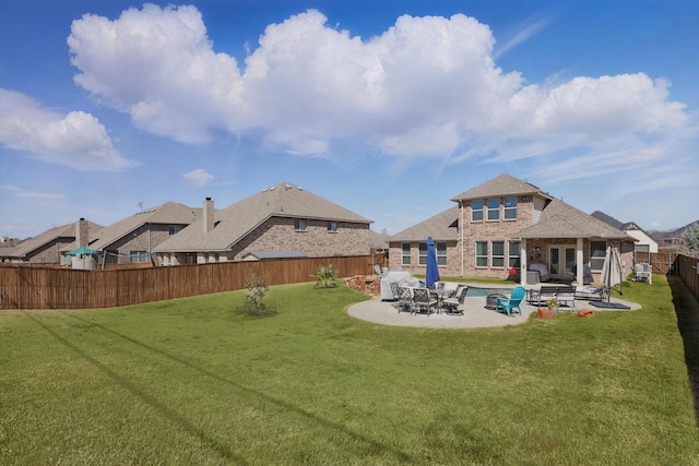 rear view of property featuring a patio area, a yard, a fenced backyard, and brick siding