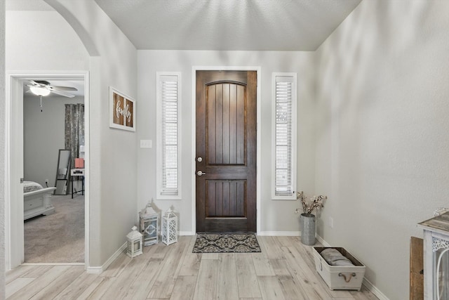 entryway with arched walkways, a healthy amount of sunlight, and wood finished floors