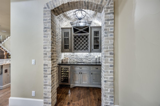 bar with beverage cooler, a sink, indoor wet bar, and dark wood-style flooring