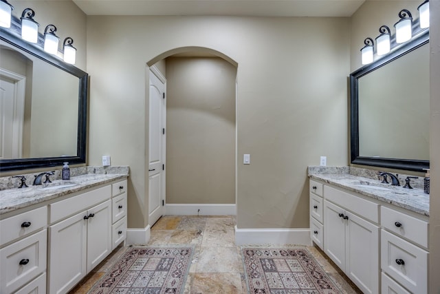 full bathroom with two vanities, baseboards, and a sink