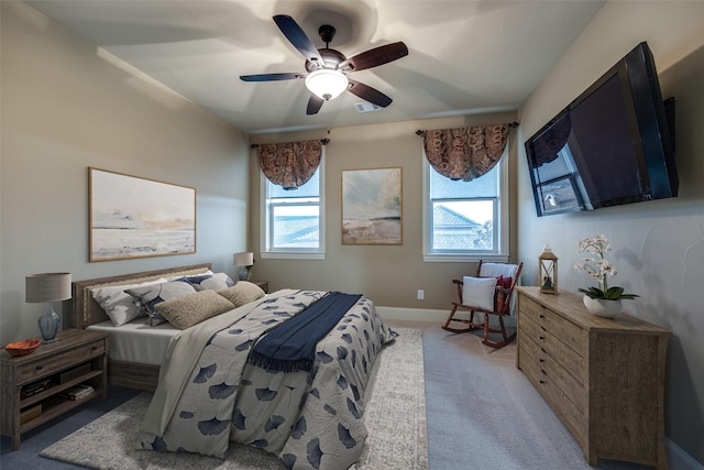 bedroom with a ceiling fan, multiple windows, light colored carpet, and baseboards