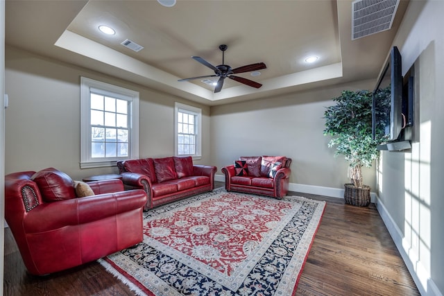 living room with a tray ceiling, baseboards, and visible vents