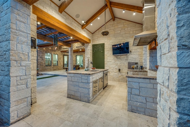 kitchen with high vaulted ceiling, beam ceiling, a sink, stainless steel dishwasher, and wall chimney range hood