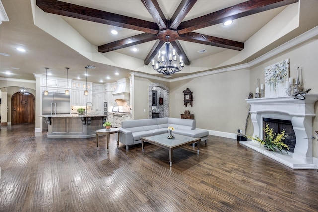 living area with beam ceiling, a fireplace with raised hearth, dark wood-style floors, arched walkways, and baseboards