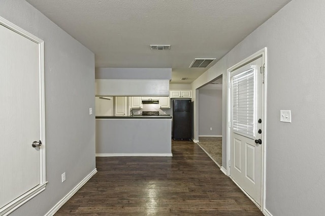 kitchen featuring dark wood finished floors, visible vents, dark countertops, and freestanding refrigerator