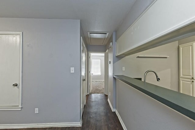 hall with dark wood-style floors, baseboards, and a sink