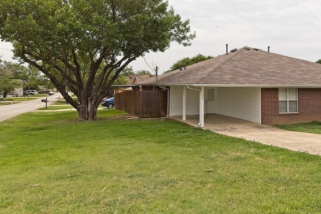 view of yard featuring a carport, concrete driveway, and fence