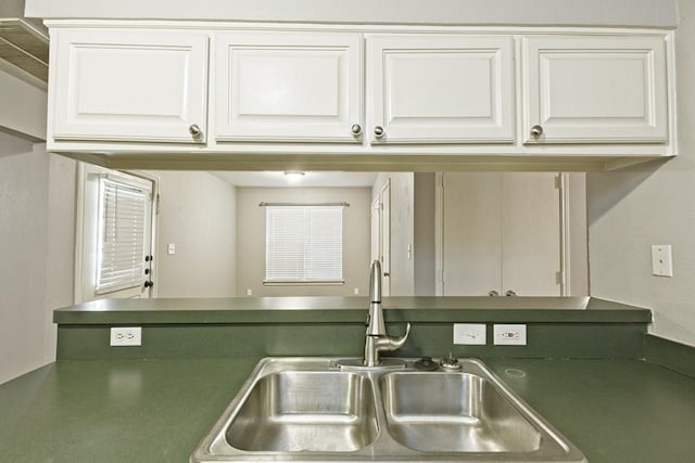 kitchen with dark countertops, white cabinetry, and a sink