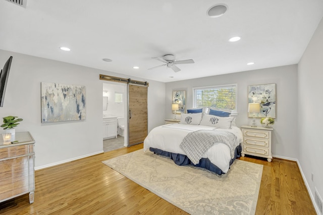 bedroom with recessed lighting, light wood-style flooring, baseboards, and a barn door