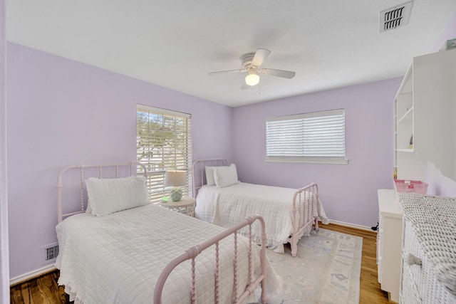 bedroom with visible vents, baseboards, a ceiling fan, and wood finished floors