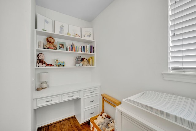 bedroom featuring built in study area and dark wood-style flooring