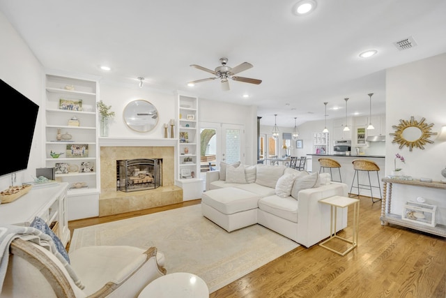 living area featuring a tiled fireplace, recessed lighting, wood finished floors, and visible vents