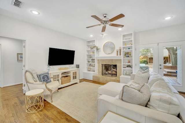 living area featuring wood finished floors, visible vents, recessed lighting, a fireplace with raised hearth, and french doors