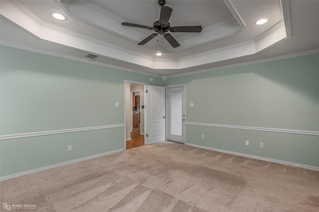 carpeted spare room featuring a raised ceiling, ornamental molding, recessed lighting, baseboards, and ceiling fan