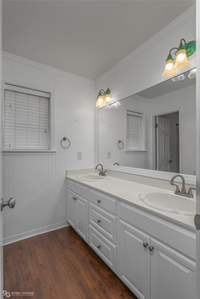 bathroom with double vanity, ornamental molding, wood finished floors, and a sink