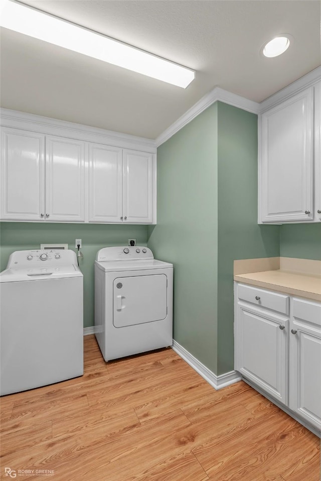 laundry room featuring washer and dryer, baseboards, cabinet space, and light wood-style flooring