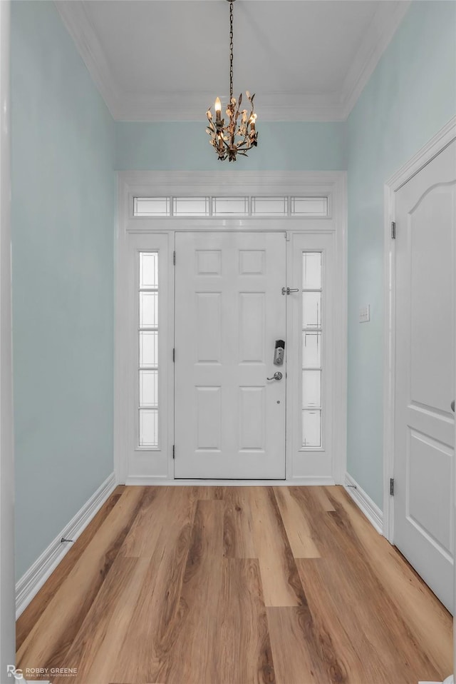 entryway featuring crown molding, light wood-style flooring, a notable chandelier, and baseboards