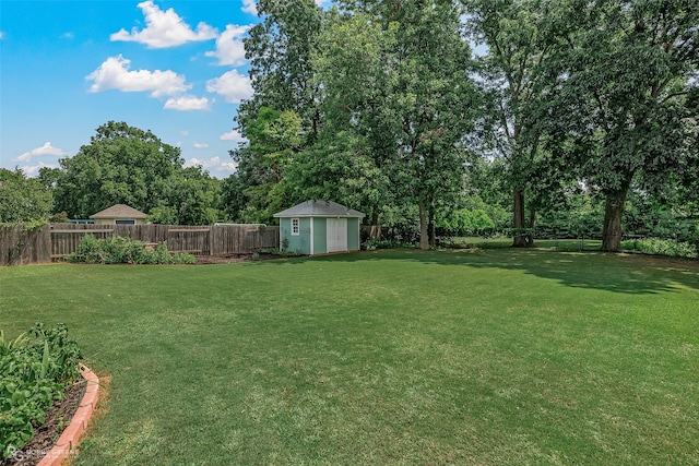 view of yard with an outbuilding, a fenced backyard, and a shed