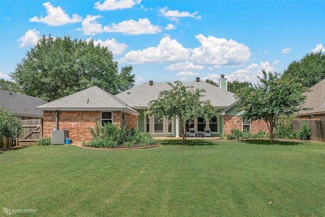 back of property featuring a fenced backyard, a yard, brick siding, a chimney, and a patio area