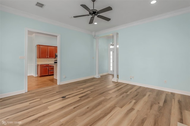 spare room featuring crown molding, decorative columns, baseboards, and light wood-type flooring