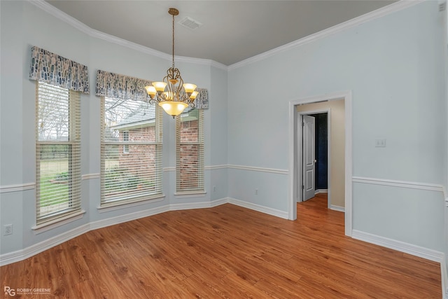 unfurnished dining area featuring an inviting chandelier, crown molding, wood finished floors, and baseboards