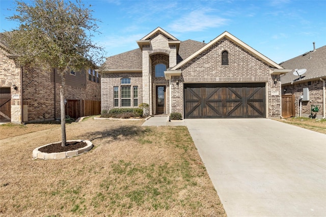 view of front of property with a front lawn, driveway, fence, a garage, and brick siding