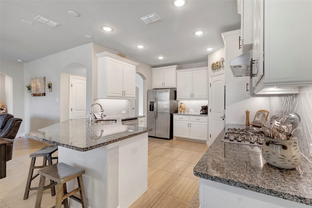 kitchen featuring range hood, visible vents, arched walkways, a sink, and appliances with stainless steel finishes