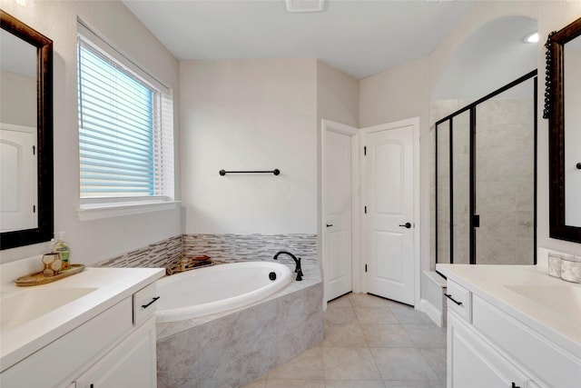 full bath with a bath, a shower stall, tile patterned floors, and two vanities