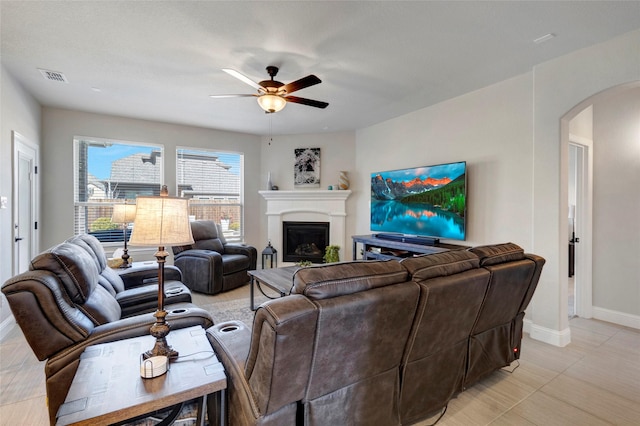 living room featuring baseboards, visible vents, a fireplace, arched walkways, and ceiling fan