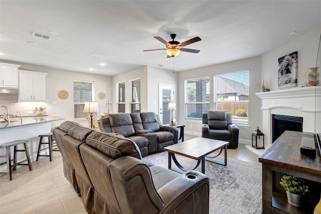 living room featuring visible vents, a fireplace with raised hearth, recessed lighting, baseboards, and ceiling fan