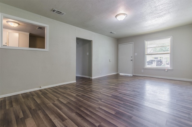 unfurnished room with visible vents, baseboards, a textured ceiling, and dark wood-style flooring