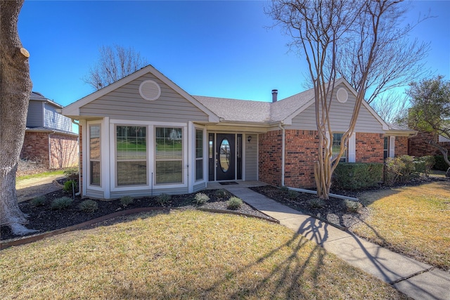 ranch-style house featuring brick siding, a shingled roof, and a front lawn