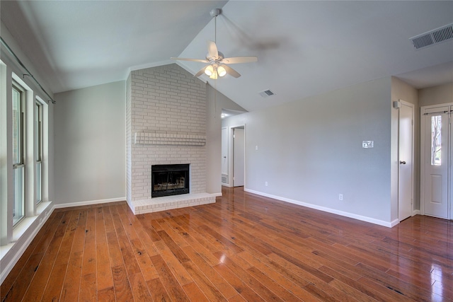 unfurnished living room with visible vents, a fireplace, vaulted ceiling, and hardwood / wood-style flooring