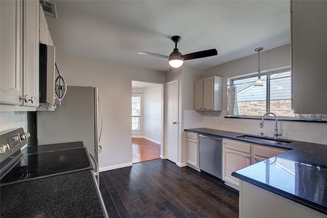 kitchen featuring a sink, dark countertops, dark wood-style floors, stainless steel appliances, and decorative backsplash