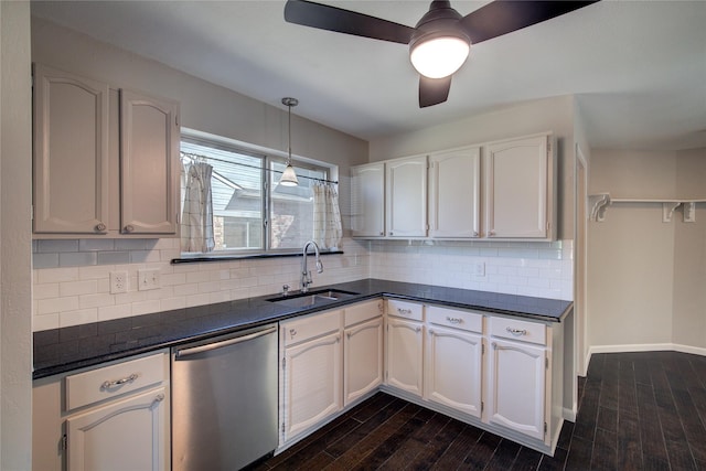 kitchen with a sink, stainless steel dishwasher, dark countertops, and dark wood-style floors