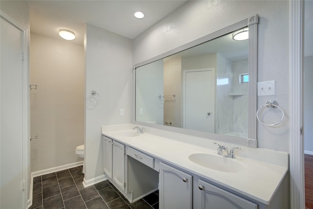 bathroom with double vanity, toilet, baseboards, and a sink